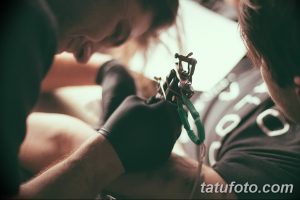 Фото процесса нанесения татуировки, демонстрирующее работу мастера и оборудование, используемое для создания рисунка на коже.